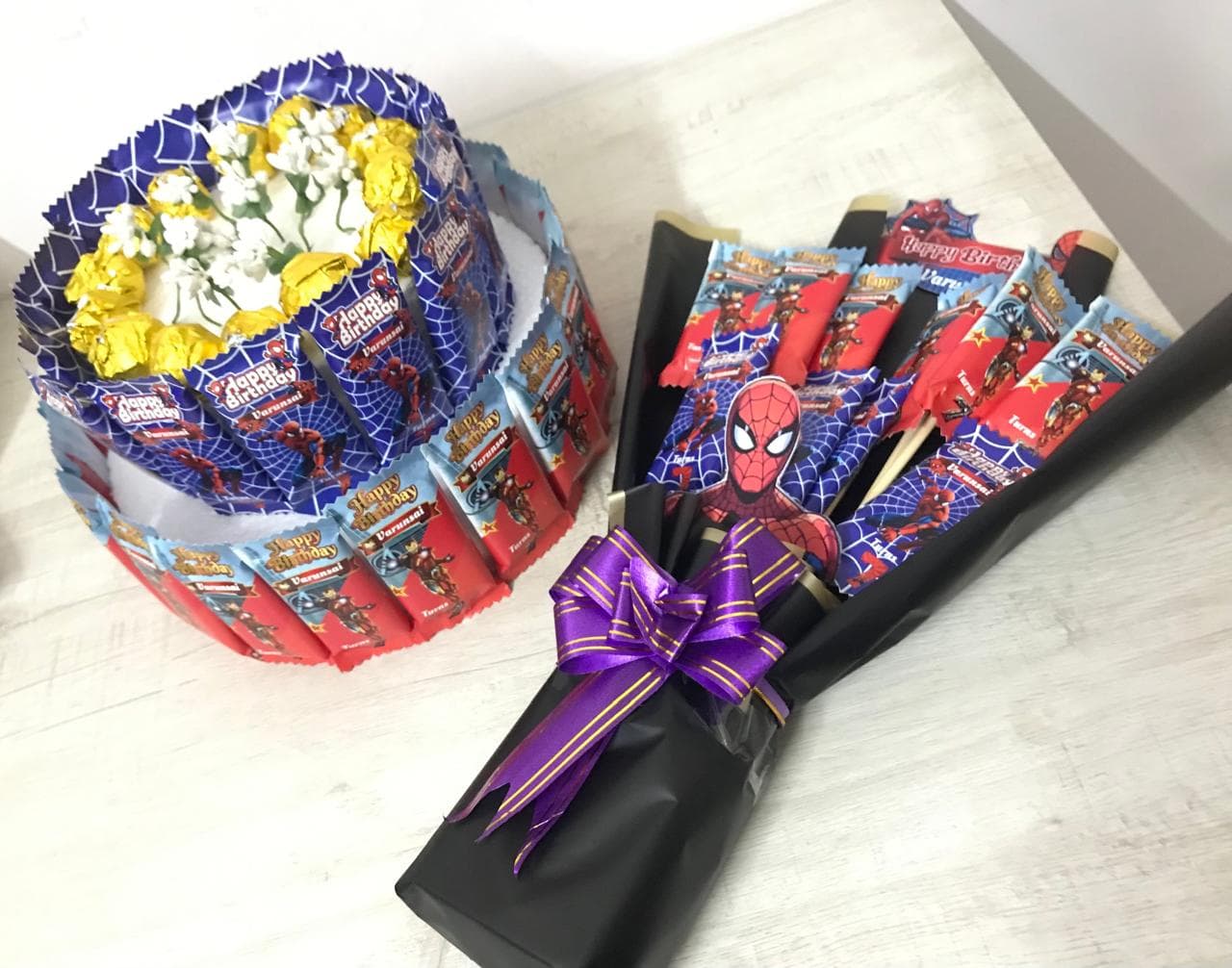 Spider-Man themed chocolate bar cake and bouquet with yellow flowers and a purple bow.