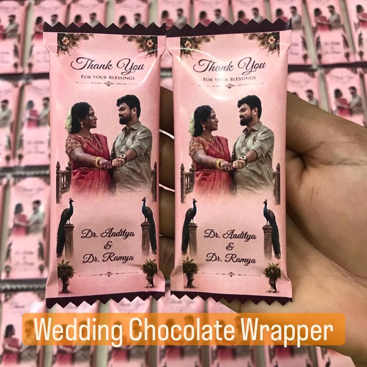 Personalized pink wedding chocolate wrappers featuring Dr. Aaditya and Dr. Ramya with peacock illustrations.