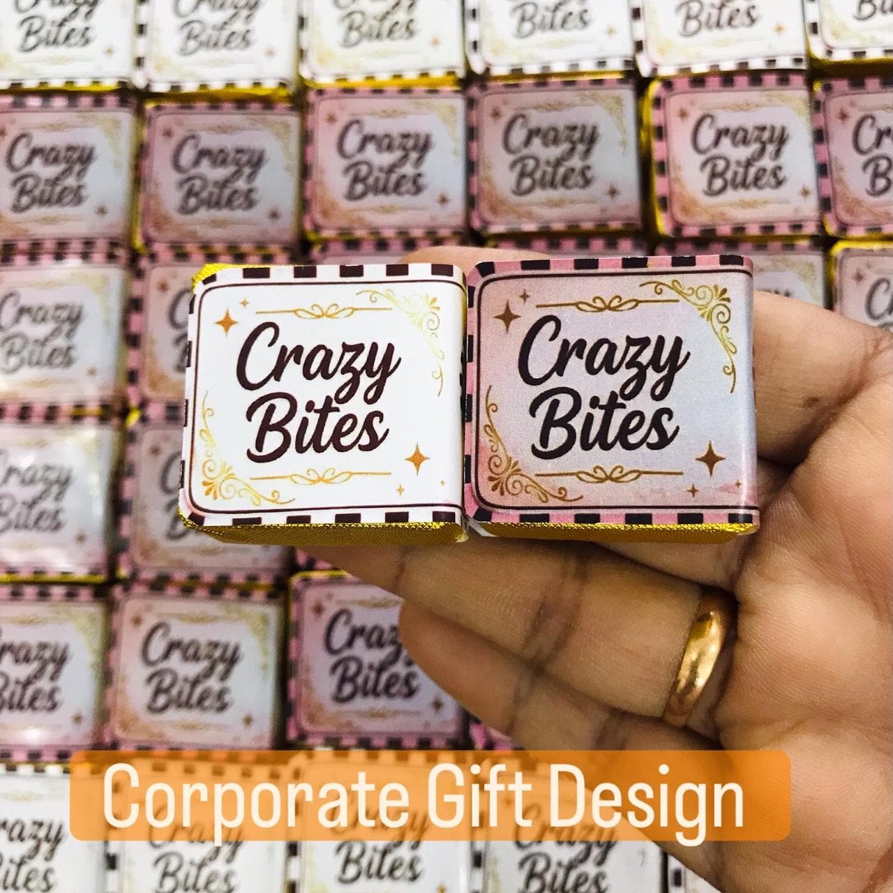 Hand holding two Crazy Bites chocolates with decorative pink and white wrappers for corporate gifting.