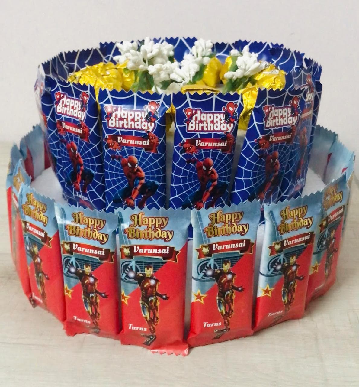 Two-tiered birthday cake made of Spider-Man and Iron Man candy bars for Varunsai.