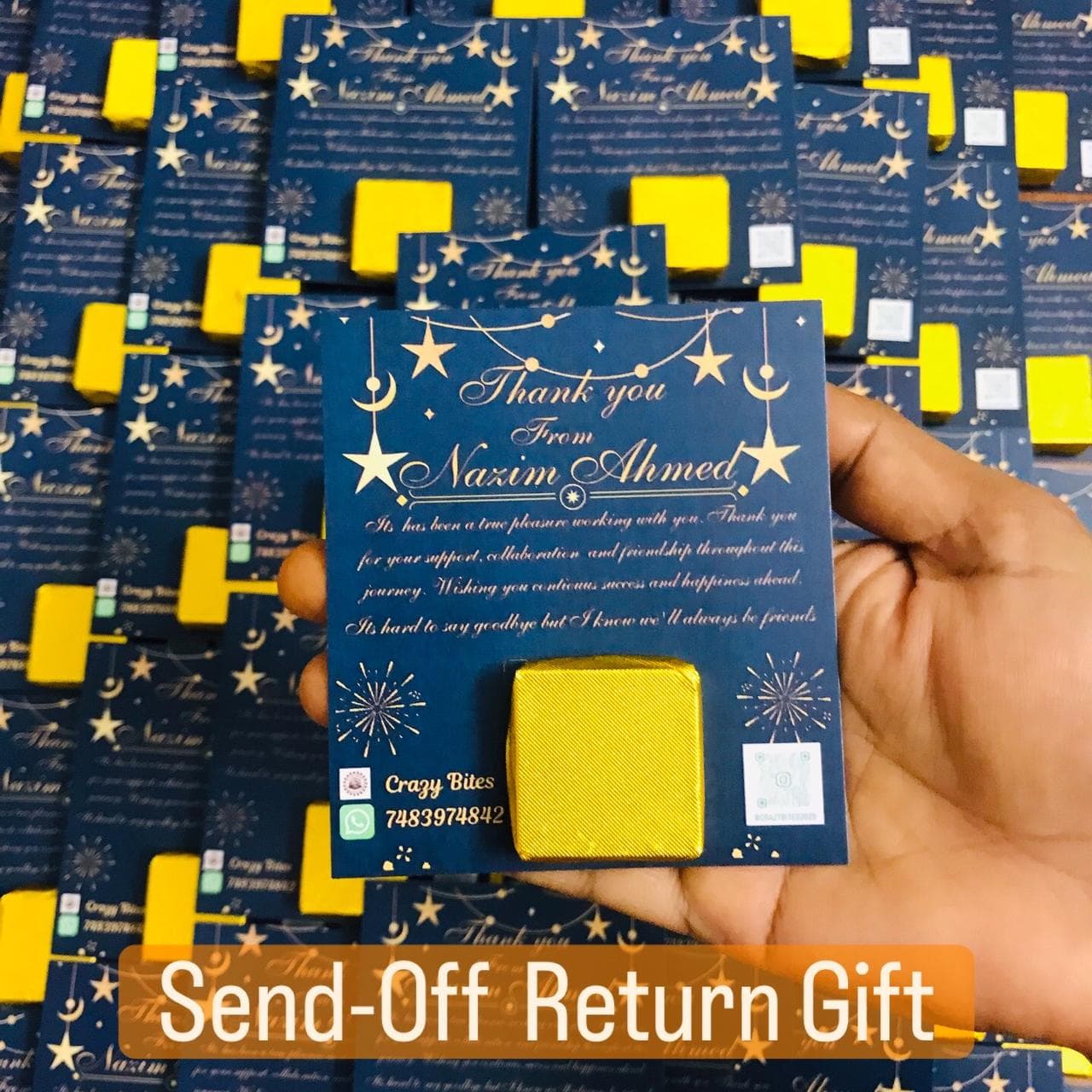 Hand holding a blue farewell card from Nazim Ahmed with a yellow square chocolate.